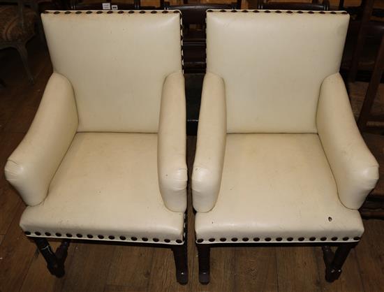 A pair of white leather studded armchairs